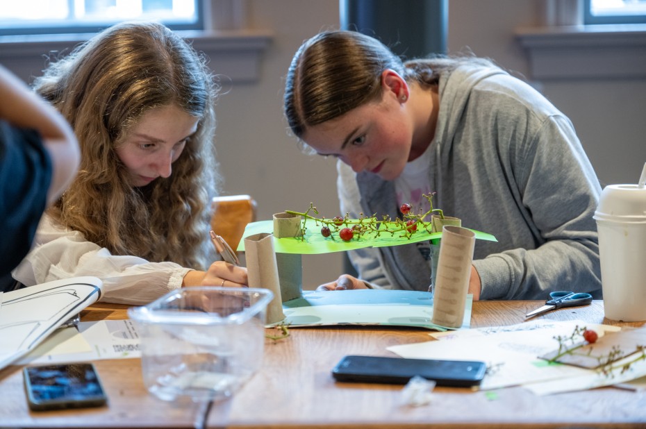 Jongeren bouwen zittend aan tafel een maquette van een pergola