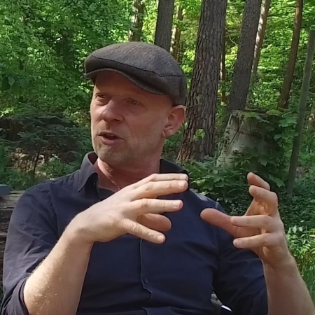 Bas Cloo met een blauw overhemd aan en een petje op in het bos