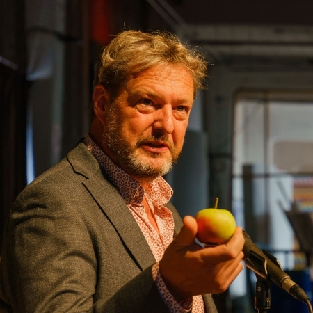 Kooes Biesmeijer sprekend met een appel in zijn hand