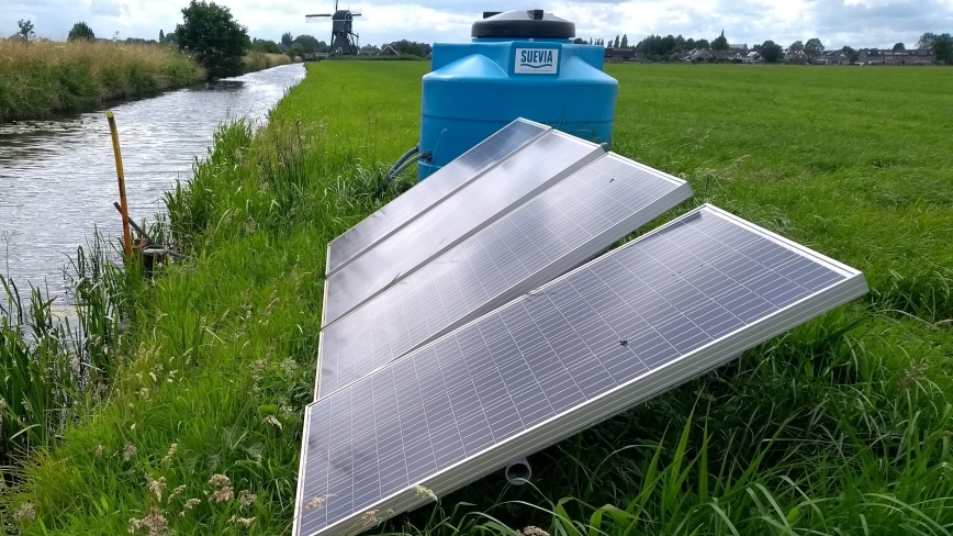 zonnepanelen met waterpomp met windmolen op de achtergrond