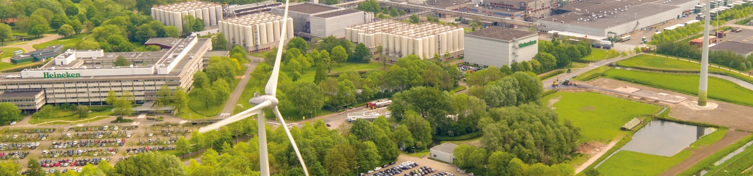 Een luchtfoto van het HEINEKEN-terrein in Zoeterwoude, omgeven door groen en windmolens