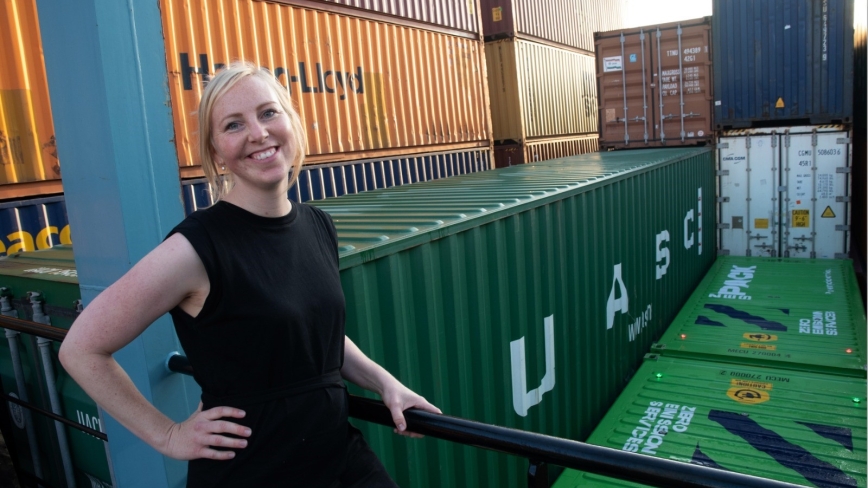 Nynke Visser staat met zwarte kleden voor een het eerste emissieloze schip dat is volgeladen met containers