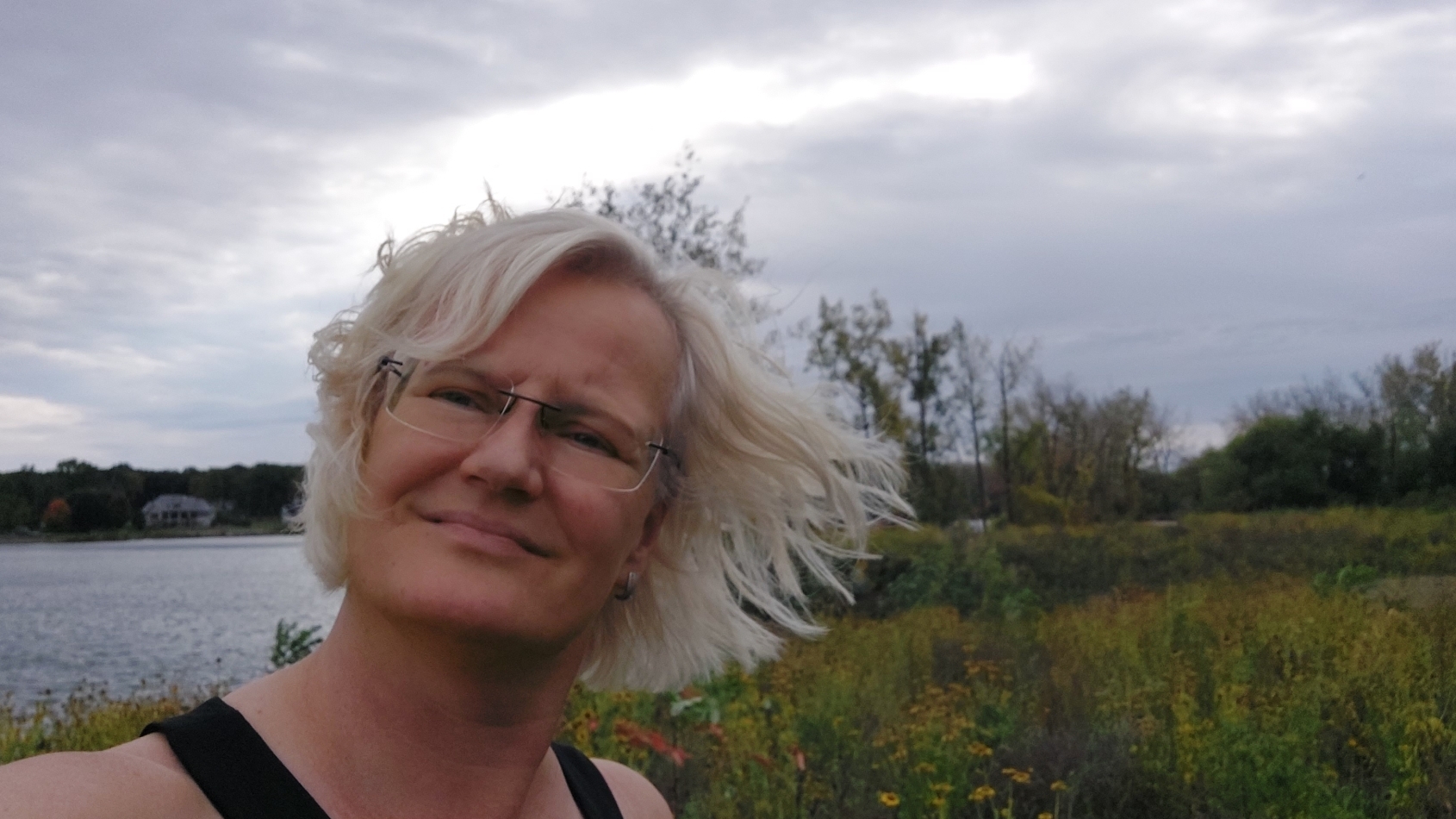 Portret van Marian Stuiver in een groen veld naast een rivier