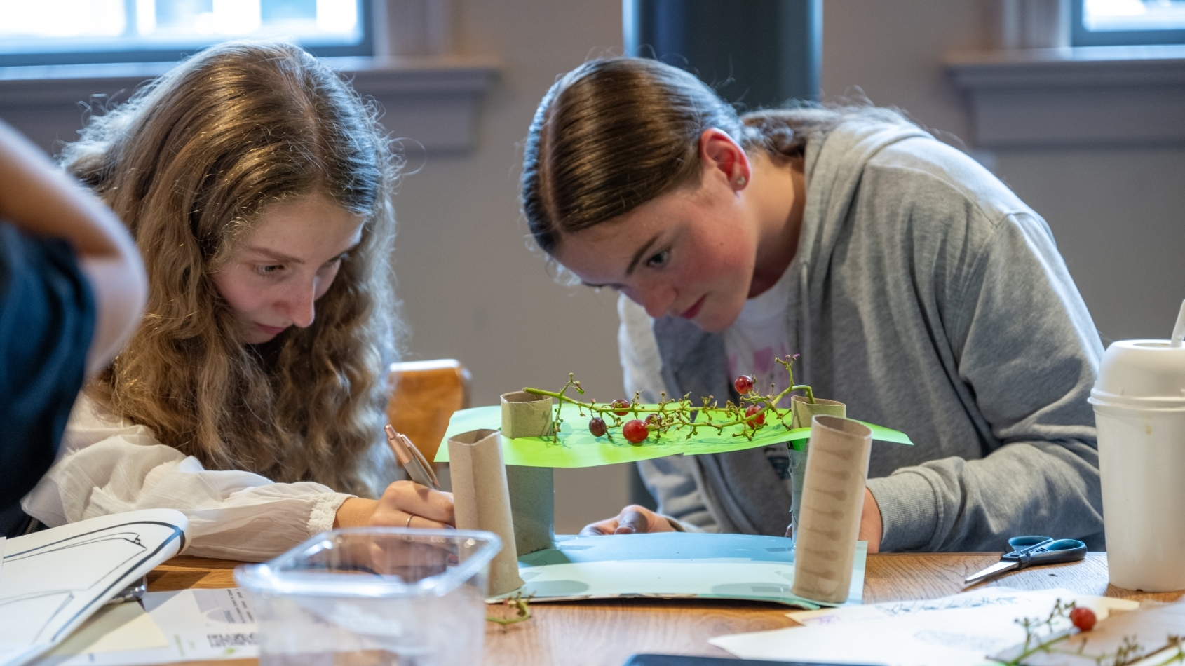 Twee leerlingen zitten aan een tafel en maken een maquette voor een overkapping van een plein