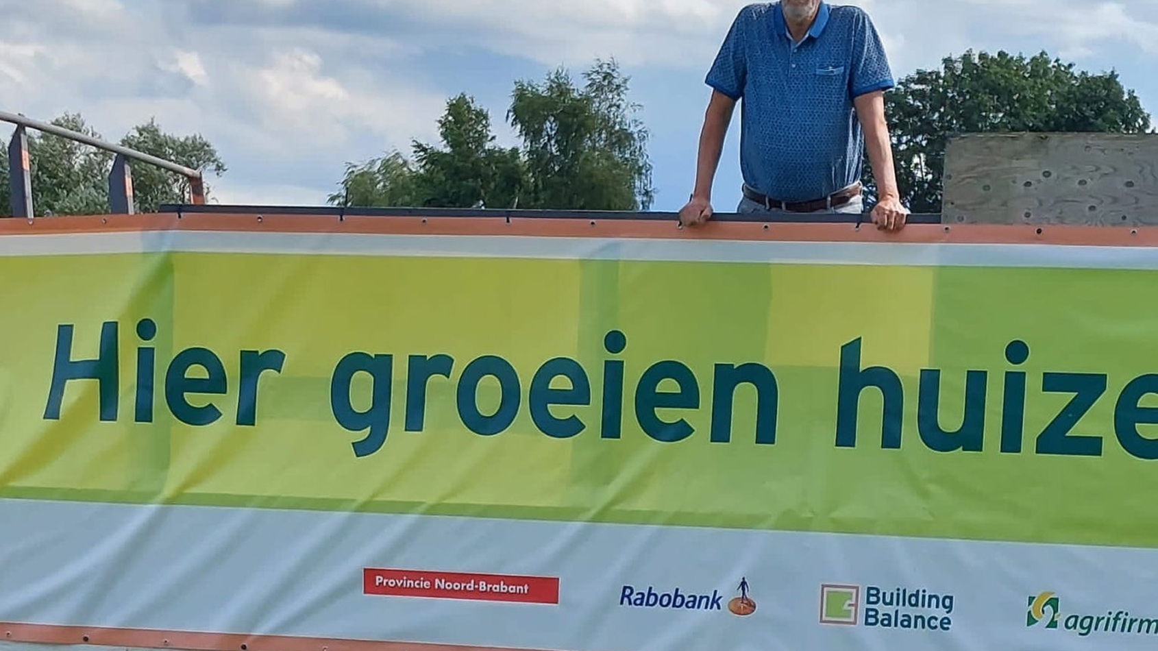 Boer Jan Versluis op een kar met de tekst 'Hier groeien huizen'